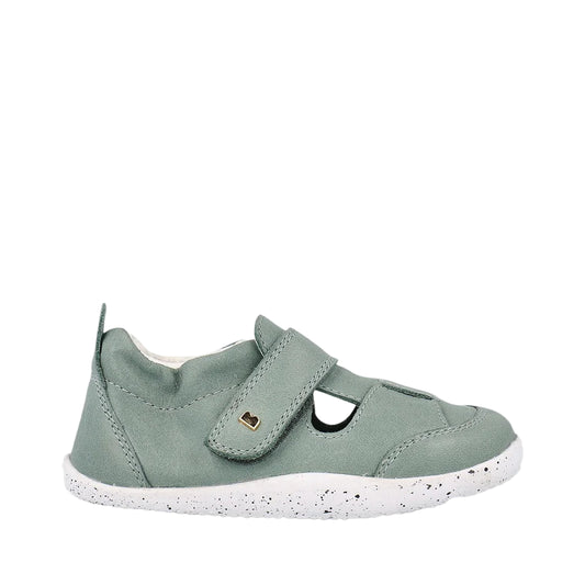 Green children's shoe with a white sole on a light gray background