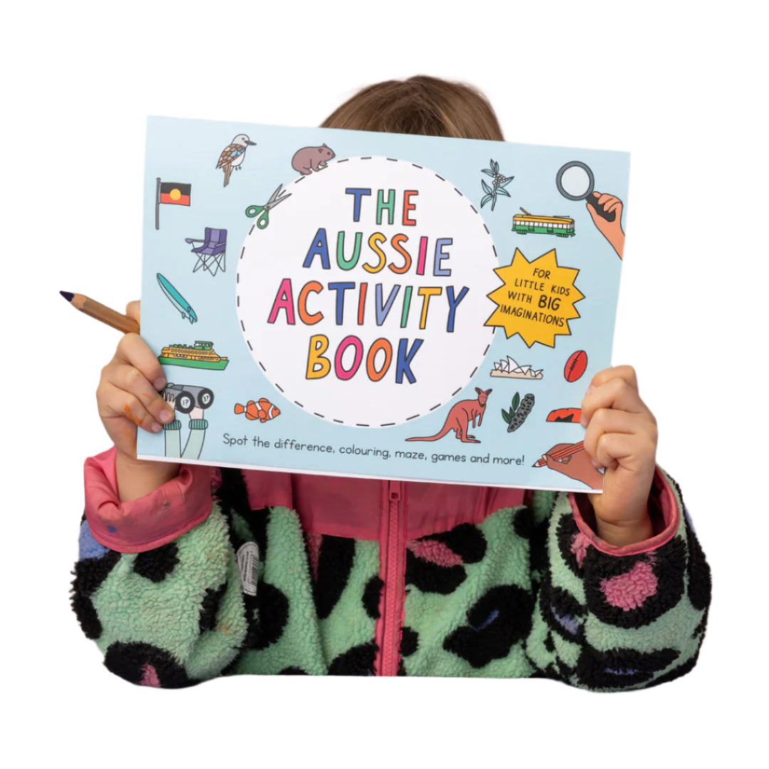 Child holding 'The Aussie Activity Book' with colorful illustrations on a pink background