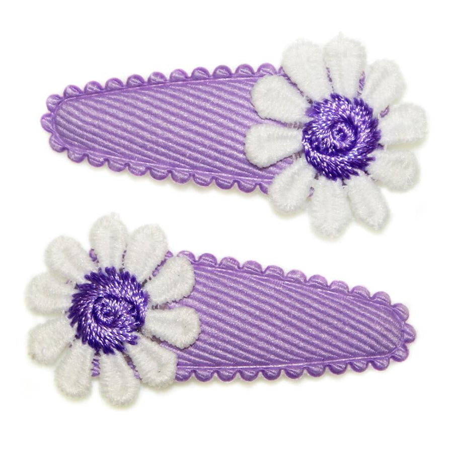 Two purple hair clips with white flower designs on a white background