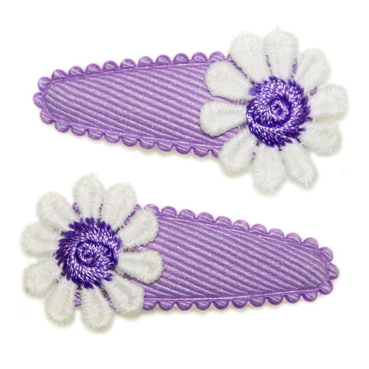 Two purple hair clips with white flower designs on a white background