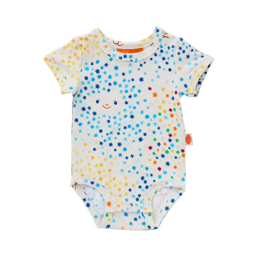 A baby short-sleeve bodysuit with an all-over colorful star print on a white base, featuring a small smiley face detail and a small orange brand tag on the side.