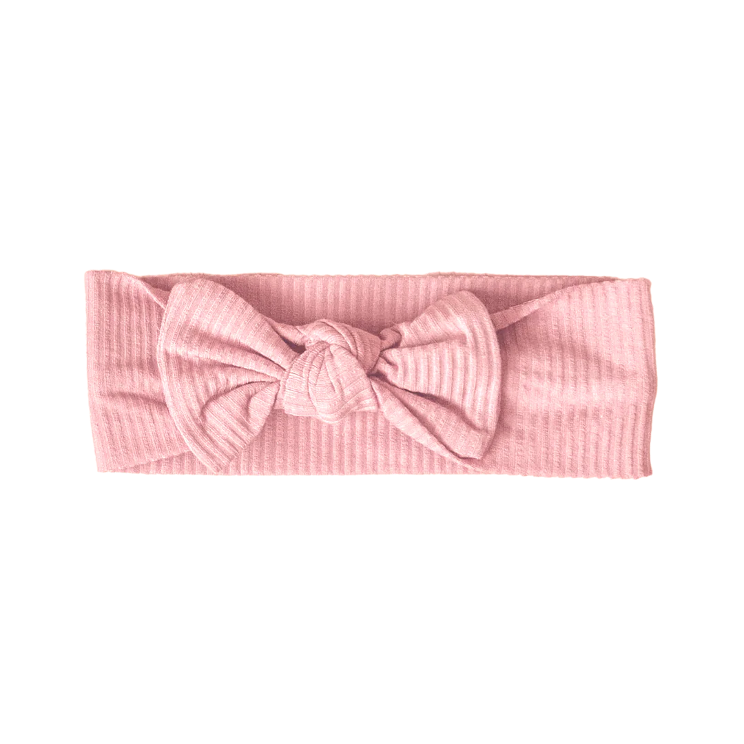 Pink ribbed headband with a bow on a white background