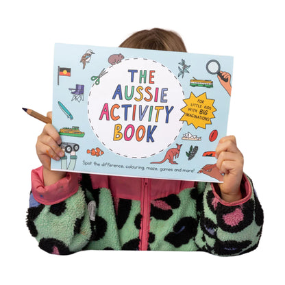 Child holding 'The Aussie Activity Book' with colorful illustrations on a pink background
