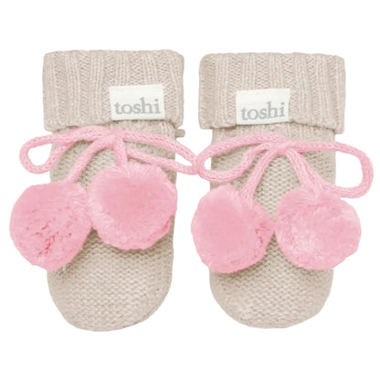 Pair of pink baby booties with beige cuffs on a white background, featuring the brand 'toshi'.