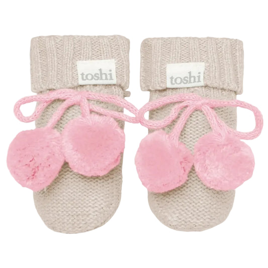 Pair of pink baby booties with beige cuffs on a white background, featuring the brand 'toshi'.