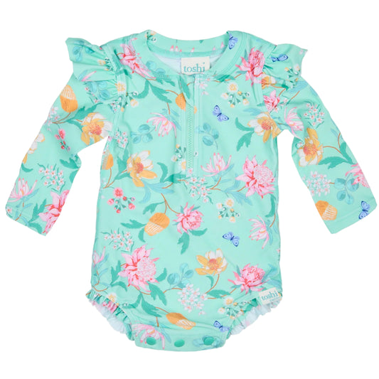 Floral-patterned baby romper with UPF 50+ sun safety label on a white background