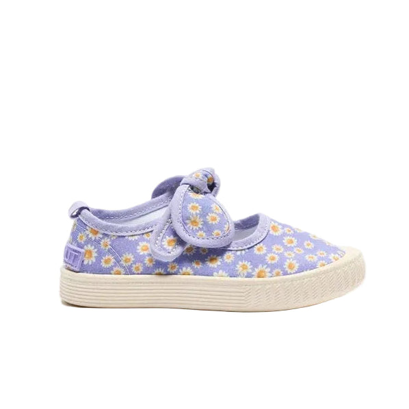A toddler's canvas slip-on shoe in lavender purple with a daisy floral pattern and a matching purple strap with a bow, set against a plain white background.