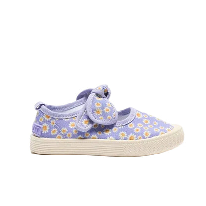 A toddler's canvas slip-on shoe in lavender purple with a daisy floral pattern and a matching purple strap with a bow, set against a plain white background.